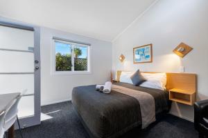 陶波Central Inn Taupo的一间卧室配有一张带书桌的床和窗户。
