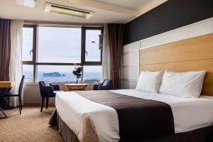 西归浦市Eastern Hotel Jeju的配有一张床、一张书桌和一扇窗户的酒店客房