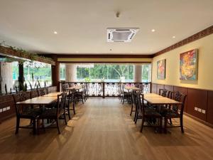 古晋The Borneo Hotel的餐厅设有桌椅和大窗户。