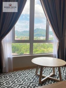 关丹Mahkota Valley (Rumah Hotel)的客房设有桌子和大窗户。