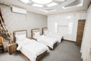 撒马尔罕Nazarxan Hotel的一间设有四张床和天花板的客房