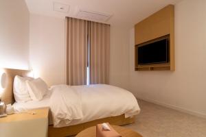 高阳市Goyang Hotel Yuji的配有一张床和一台平面电视的酒店客房