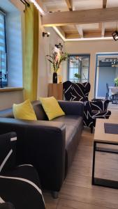 HinterseeHaus Julia的客厅配有黑色沙发和黄色枕头