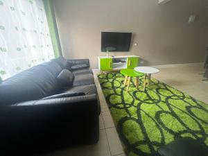 内罗毕Juke's Serene Westlands Villa的客厅配有黑色沙发和绿色地毯。