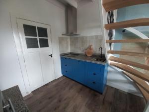 奥门Vakantiewoning - Veurom的一间设有蓝色橱柜和楼梯的厨房