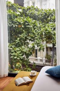 河内Eliana Signature Hanoi Hotel的一张桌子,里面有两本书,在窗边边喝着咖啡