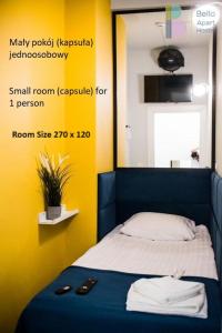 华沙Bello ApartHostel的小房间设有一张黄色墙壁的床