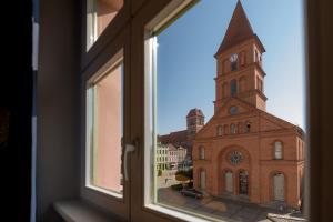 托伦AtHome Toruń Apartamenty的教堂的窗户景,带钟楼