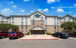 沃思堡WoodSpring Suites Fort Worth Fossil Creek的停车场内有车辆的旅馆