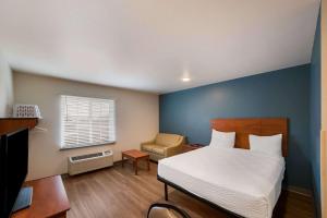沃思堡WoodSpring Suites Fort Worth Fossil Creek的一间卧室配有一张床、一张桌子和一把椅子