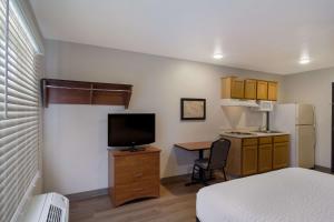 杰克逊维尔WoodSpring Suites Jacksonville I-295 East的小房间设有一张床和一张书桌及电视