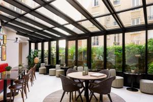 巴黎Hôtel Moderniste的餐厅设有桌椅和大窗户。