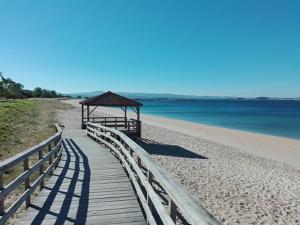 博伊罗Ático con magnifica terraza en Boiro的通往海滩凉亭的木板路