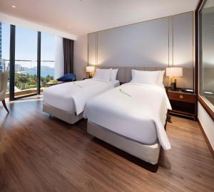 芽庄Best Western Premier Marvella Nha Trang的配有大窗户的酒店客房内的两张床