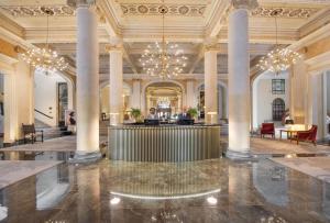 巴勒莫艾特德斯帕尔梅斯大酒店的大厅里有柱子,有人坐在桌子上
