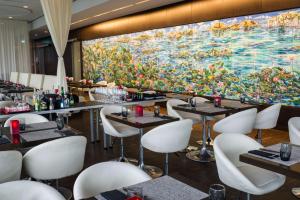 科隆art'otel cologne, Powered by Radisson Hotels的餐厅在一幅大画前面,配有桌椅