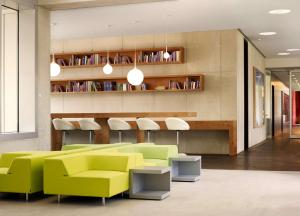 科隆art'otel cologne, Powered by Radisson Hotels的客厅配有黄色和绿色的家具和架子