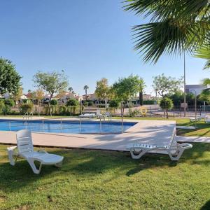 穆尔西亚Un Oasis en Hacienda del Álamo的游泳池畔的两把椅子和一张床