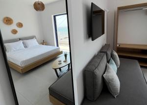 DiakoftiKythera Beach Apartments的一间卧室配有一张床、一张沙发和一台电视