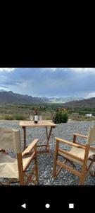 卡奇Cabaña Abra del Monte Monohambiente的一张桌子、两把椅子和一瓶葡萄酒