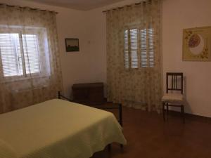奥尔贝泰洛Casale Gli Ulivi的一间卧室设有床、两扇窗户和一把椅子
