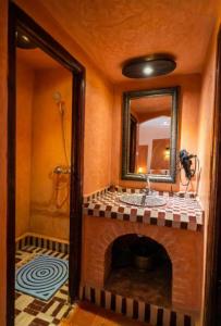 梅尔祖卡Riad family的一间带壁炉、水槽和镜子的浴室