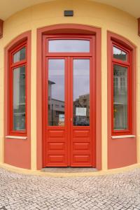 波瓦-迪瓦尔津A'MAR by Alojamento Ideal的大楼的红色门,有三个窗户