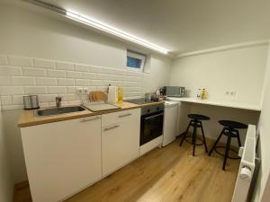 普福尔茨海姆Mini Apartment mit Bad und Küche的厨房配有白色橱柜、水槽和2把凳子