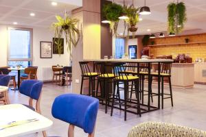 昂热Odalys City Angers Centre Gare的餐厅设有酒吧,配有桌椅