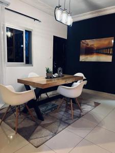 雅温得Roswell Luxury Properties Yaoundé - Quartier FOUDA的一间带木桌和白色椅子的用餐室