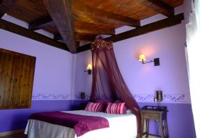 特拉马卡斯蒂利亚圣安娜旅馆的一间卧室设有一张紫色墙壁和木制天花板的床。
