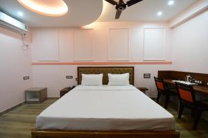 布巴内什瓦尔HOTEL SUSHREE INTERNATIONAL的卧室配有一张床和一张桌子及椅子