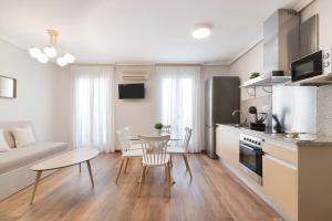 马德里玫瑰中心公寓的厨房以及带桌子和沙发的客厅。