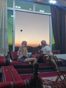 瓦迪穆萨Petra paradise home的两个女孩坐在沙发上看日落