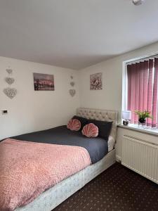哈德斯菲尔德Bv Cozy Deighton Studio with Free Parking - Budget-Friendly Stay的一间卧室配有一张带粉色毯子的床和窗户。