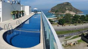 里约热内卢Atlantico Sul Hotel的一座游泳池,位于一座毗邻大海的建筑的顶部