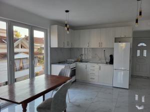 卡瓦达尔奇Jordanovi Premium Apartment的厨房配有木桌和冰箱。