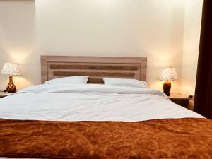 杰拉什Dream house hotel jerash的一间卧室配有一张带两盏灯的大型白色床。