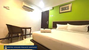 安邦Hotel Grand Palace Ampang的一间卧室设有一张床铺和一张桌子,还有一面绿色的墙壁
