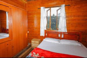 乌提Sandy Wood House Ooty - 2Bhk Villa的小木屋内一间卧室,配有一张床和一个窗户