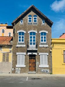 普拉亚KAZARÃO DI MAVETE - Guesthouse的棕色砖砌的建筑,设有白色的窗户和门
