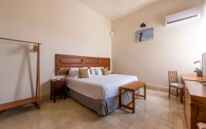 梅里达Villa Orquídea Boutique Hotel的一间卧室配有一张床、一张桌子和一个水槽