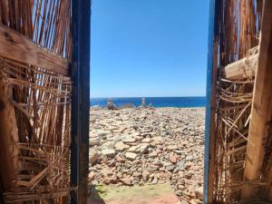 达哈布Cosmos Camp的从大楼内可以欣赏到岩石海滩的景致