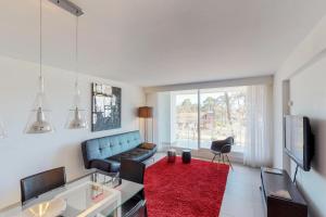 埃斯特角城Oceana Suites en Yoo, con piscina interior climatizada的客厅配有蓝色的沙发和红色地毯。