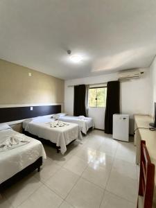 伊瓜苏Hotel Castelo Branco的酒店客房设有两张床和窗户。