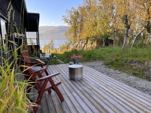 特罗姆瑟Håkøya Lodge的木甲板上设有长凳和桌子