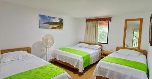 巴亚索拉诺Playa de Oro Lodge的一间卧室配有两张床和风扇