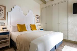 塞维利亚La Rosa de la Alfalfa的卧室配有一张带黄色枕头的大型白色床。