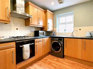 利兹Cheerful two-bedroom townhouse near Leeds and York的厨房配有木制橱柜、洗衣机和烘干机