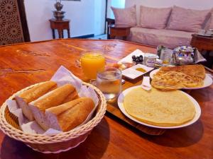 梅克内斯Riad Sibari的一张桌子,上面放着两篮面包和橙汁